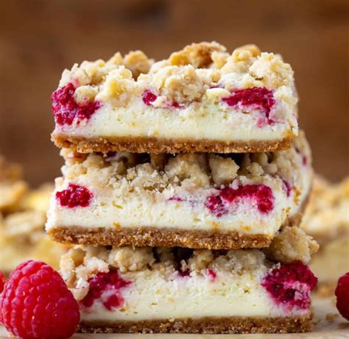 Raspberry bar on a piece of parchment paper with raspberries next to it.